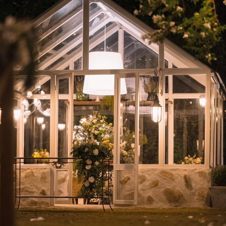 Poltrona em fibra natural e tapete de fibra em estufa iluminada por luz natural, cercada de plantas